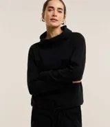 Blusa de malla brush acanalada color negro, con cuello alto degagê, mangas largas y lazo en la parte baja.