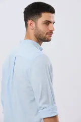 Camisa de lino y algodón color beige, de manga larga, con cuello mao y cierre frontal con botones. Presenta un pequeño bordado al tono en el pecho.