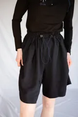 Bermuda holgada negra con cintura elastizada y hebillas de ajuste.