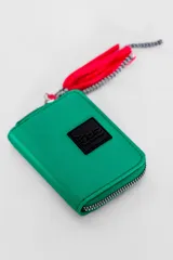 Billetera verde esmeralda con cierre de cremallera y detalle de borla roja y negra.