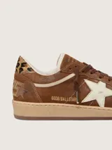 Zapatillas Golden Goose modelo Ball Star, confeccionadas en gamuza marrón con detalles en animal print de leopardo en la puntera y el talón. Presenta la característica estrella lateral en cuero crema, cordones marrones y suela de goma camel.