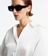 Camisa de satén color verde oliva, de manga larga con puños abotonados y cuello inglés.