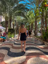 Vestido corto negro con escote halter y cierre frontal con cremallera dorada.