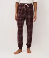 Pantalón de pijama tipo jogger confeccionado en tejido peach touch de color bordó, con estampado de cuadros y pequeños detalles de corazones. Posee cintura elástica con cordón de ajuste en color rosado y puños elastizados en los tobillos.