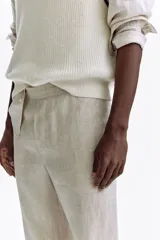 Pantalón de lino liviano para hombre, de corte regular fit y color beige. Presenta cintura elástica con cordón de ajuste oculto, bolsillos laterales discretos y un bolsillo trasero insertado.