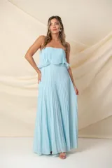 Vestido largo strapless de gasa plisada color celeste, con volados en el busto y corte en la cintura.