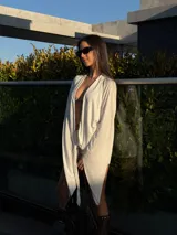 Vestido corto blanco de manga larga, con diseño cruzado, escote en V pronunciado y detalle de nudo frontal.
