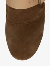 Bota de montar de caña alta y diseño holgado, confeccionada en cuero con acabado de gamuza color marrón. Presenta múltiples correas de cuero liso en color beige con hebillas metálicas doradas a lo largo de la caña y el empeine. Posee un taco bajo de aproximadamente 2,5 cm.