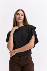 Remera negra de algodón con mangas cortas que presentan volados dobles, aportando volumen y movimiento a la prenda.