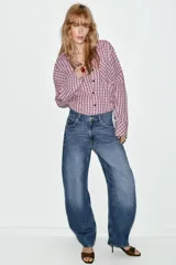 Jeans de tiro alto con diseño barrel, caracterizado por una silueta curvada y holgada en la zona de los muslos y rodillas, estrechándose hacia el tobillo. Cuenta con cinco bolsillos y cierre frontal con cremallera y botón.