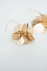 Par de aros colgantes dorados con diseño de flores compuestas por múltiples pétalos metálicos con textura estriada.
