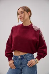 Sweater de punto color bordó, de corte cropped y mangas largas con puños ajustados. Presenta detalles decorativos de apliques bordados con lentejuelas y perlas en la zona de los hombros.