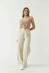 Top de punto color rosado con escote en V, tirantes finos y detalle de fruncido central con cordón ajustable. Presenta un diseño corto y ajustado al cuerpo.