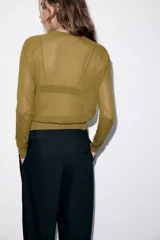 Jersey de punto fino con cuello redondo y manga larga con puños elásticos. Presenta un diseño minimalista con costuras visibles en los hombros.