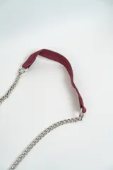 Cartera de hombro color azul marino, con solapa frontal decorada con tachas en forma de estrellas plateadas. Los bordes están adornados con un detalle de cadena entrelazada y la correa es una combinación de cadena plateada y una sección de cuero sintético.