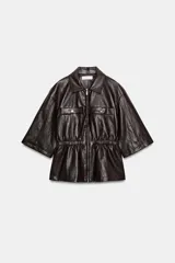 Chaqueta de efecto piel con cuello solapa, manga corta y cintura elástica. Presenta cierre frontal con cremallera y bolsillos decorativos en el frente.