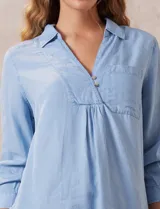 Blusa celeste de lyocell con cuello con solapa, escote en V y cierre con botones. Tiene un bolsillo en el pecho, mangas 3/4 con puño y botón.