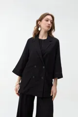 Blazer negro de corte recto y holgado, con doble botonadura frontal, solapas clásicas y mangas tres cuartos con costuras pespunteadas en contraste.