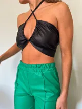 Top negro de cuero sintético con tiras cruzadas en el cuello y abertura en el pecho.