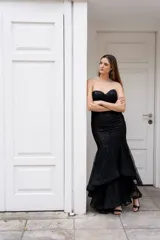 Vestido largo negro strapless tipo corset con tul y lentejuelas, de corte sirena y falda con volados.