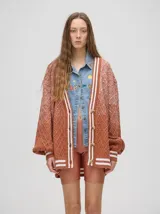 Cardigan de punto con diseño degradé en tonos tierra, patrón de rombos en relieve, cuello en V con cartera de botones y puños con rayas blancas y marrones.