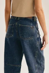Jean barrel de tiro alto en denim azul con lavado desgastado, silueta curva y costuras decorativas a la altura de la rodilla.