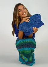 Cartera de mano tipo sobre color fucsia, confeccionada en rafia con flecos.