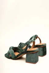 Sandalia de tacón cuadrado medio, confeccionada en terciopelo negro. Presenta un diseño de tiras cruzadas con nudo en la parte delantera y una tira ajustable con hebilla en el tobillo.