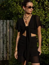 Conjunto de camisa manga larga y falda corta a rayas verticales color beige y blanco. La falda tiene volados y frunces.