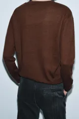 Jersey de punto liso color verde, con cuello redondo y manga larga. Confeccionado en hilatura de lana 100% con tacto suave.