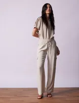 Pantalón cargo de lino a rayas verticales grises y blancas, marca Marissa Olivia. Pretina ancha elastizada con lazo de ajuste, bolsillos inclinados delanteros y bolsillos laterales con botón.