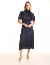 Vestido midi de satén color azul marino, marca Julia Jordan. Presenta cuello alto con punto smock, mangas amplias de estilo fluido y cintura elastizada también con punto smock. La falda tiene una caída fluida con plisado. Cierre posterior con abertura de ojal y botones. Incluye forro interno a tono.