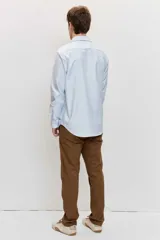 Camisa de manga larga con cierre frontal de botones y cuello clásico, color celeste con sutiles rayas verticales.