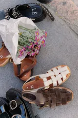 Sandalias tipo huarache de cuero con diseño de tiras entrelazadas, punta cerrada y cierre con hebilla lateral. Cuentan con suela plana y plantilla con logo grabado.