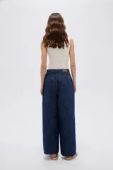 Pantalón jean azul de tiro medio, corte holgado y diseño amplio con pinzas en la parte frontal.