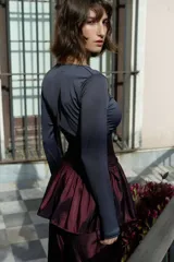 Minifalda negra de tafeta con cintura alta elastizada, diseño con volado y lazos laterales ajustables.