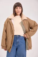 Campera acolchada reversible con capucha, diseño de matelassé, cierre frontal y puños elásticos. Presenta un lado en color verde oliva y otro en color beige.