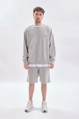Bermuda de corte recto con efecto lavado en color gris claro, confeccionada en tejido de algodón con cintura elástica y cordón ajustable.