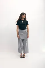Pantalón palazzo gris con sobrefalda asimétrica atada a la cintura.