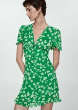 Vestido corto de tejido fluido color verde con estampado floral en tono crema. Presenta escote en pico con cierre de lazo frontal, mangas cortas con vuelo, diseño entallado en la cintura y bajo con volante.