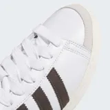 Championes Adidas Jabbar Hi de corte alto, con exterior de cuero blanco, detalles de gamuza marrón en las icónicas tres tiras y en el cuello, y suela de caucho en tono crema.