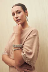 Vestido corto color rosa nude de punto, con mangas cortas y apliques de tachas plateadas en las terminaciones de las mangas.