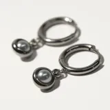 Aros plateados tipo argolla con dije colgante de perla sintética gris.