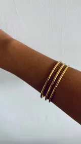 Set de tres brazaletes dorados con textura martillada.