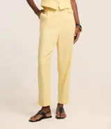 Pantalón carrot de cintura alta, confeccionado en mezcla de viscosa y lino, con trabillas en la cintura, pliegues y solapas con botón decorativo. Presenta un corte holgado en las caderas que se estrecha hacia los tobillos.