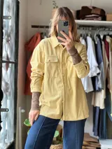 Sobrecamisa de pana color amarillo manteca, de corte oversize, con mangas largas, bolsillos frontales con solapa y cierre de botones. Presenta detalles de costuras bordadas en contraste.