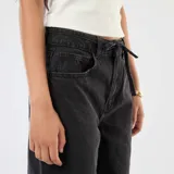Pantalón de jean corte wide leg, de tiro alto y color gris lavado, con cierre frontal y cinturón fino del mismo tejido.