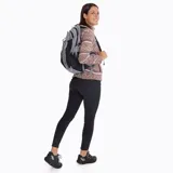 Mochila técnica de 22 litros marca Merrell, diseñada para actividades outdoor. Presenta un diseño bicolor en gris y negro, con múltiples compartimentos, bolsillos laterales para botellas, respaldo acolchado con malla transpirable, cinta frontal tipo daisy chain para accesorios y correas ajustables con silbato de emergencia.
