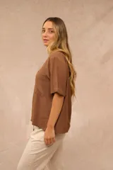 Blusa marrón de corte holgado, con cuello redondo, mangas cortas con vuelta y un bolsillo aplicado en el pecho.
