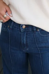 Jean de tiro medio en color azul oscuro, con costura vertical decorativa en el centro de cada pierna y cierre frontal con botón metálico.